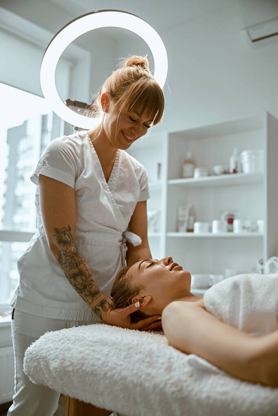 Adulto especialista do sexo feminino está fazendo massagem no pescoço para um jovem cliente feminino bonito natural - Foto, Imagem
