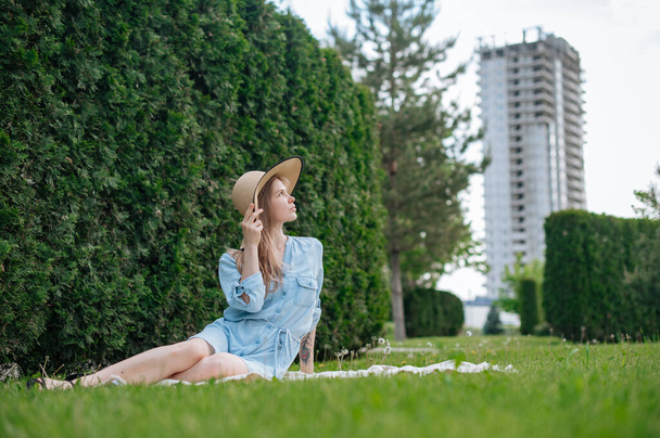 The girl dreams of a new apartment. Romantic girl with hat on picnic in park. - Photo, Image