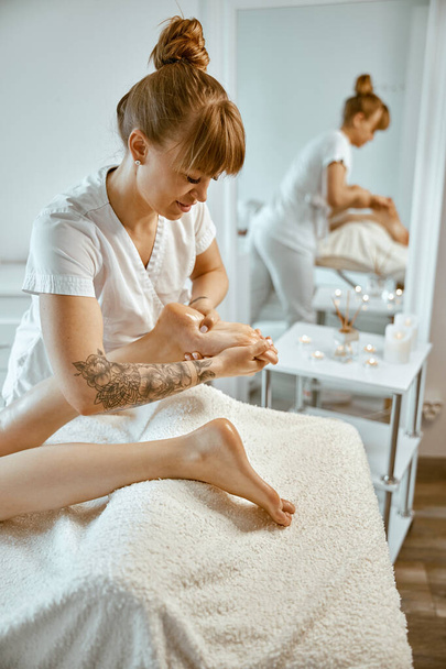 Professional caucasian specialist is doing leg message at modern minimalistic salon - Zdjęcie, obraz