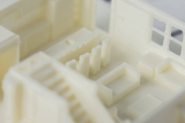 Close-up of 3D model of the house floor with staircase and furniture printed on a 3D printer with white filament by FDM technology. - Photo, image