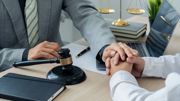Attorney-consultants hold clients' hands with trust. The center of lawyers and clients are discussing on a table with scales and hammers with laptops and notebooks. legal advisor concept - Photo, Image