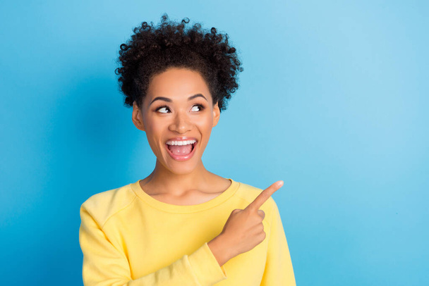 Photo of amazed happy woman point finger look empty space shocked news smile isolated on blue color background - Zdjęcie, obraz