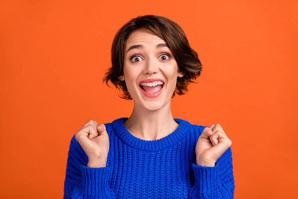 Photo portrait bob haired woman smiling in casual sweater gesturing like winner isolated bright orange color background - Photo, image