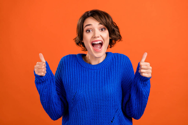 Portrait of attractive successful cheerful girl showing thumbup ad advert isolated over bright orange color background - Photo, image