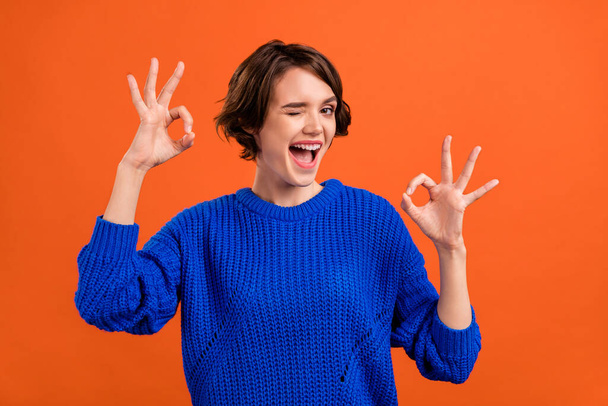 Photo portrait woman smiling showing okay gestures winking isolated vibrant orange color background copyspace - Foto, Bild