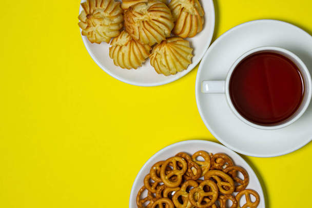 Чайна перерва. Чашка чаю з цукерками на жовтому тлі. Легка закуска
 - Фото, зображення