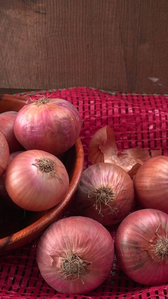 Cebollas rojas frescas en un tazón de madera
 - Foto, Imagen