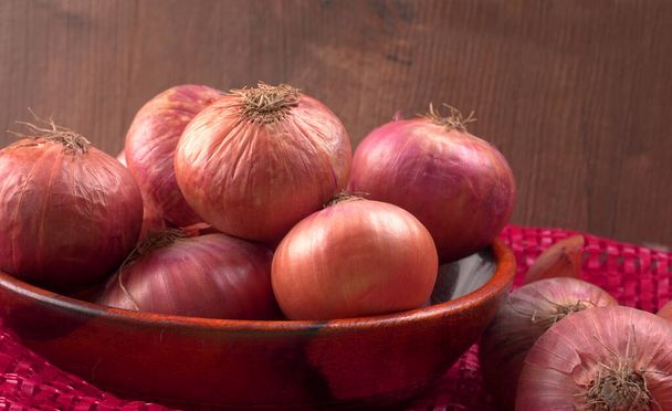 Fresh red onions in a wooden bowl - Photo, Image