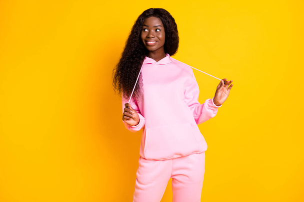 Photo of shiny charming dark skin woman dressed pink hoodie looking empty space isolated yellow color background - Foto, immagini