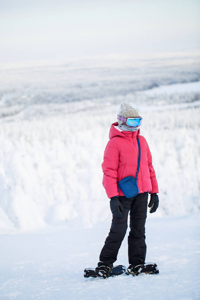 Cute pre-teen girl hiking in snowshoes in winter forest among snow covered trees in Lapland Finland - Fotografie, Obrázek