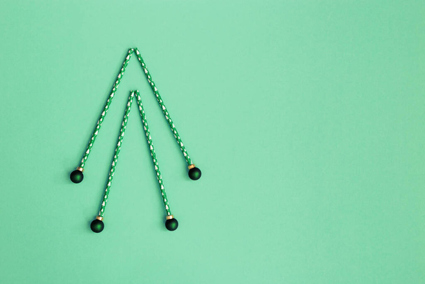 Creative christmas tree from paper drinking straws with new year ornament on green mint background with copy space. Minimal celebration concept for xmas. Flat lay. - Foto, Imagem