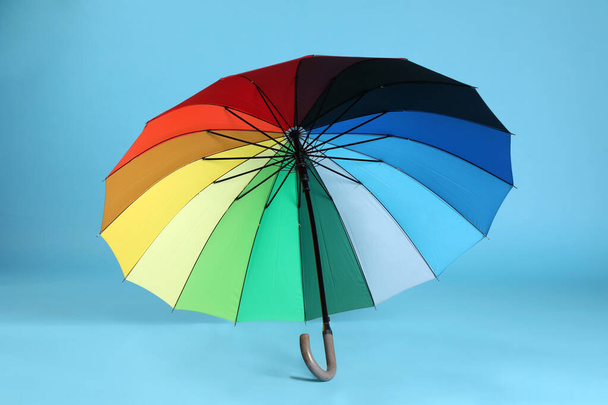 Stylish open bright umbrella on light blue background - Foto, imagen