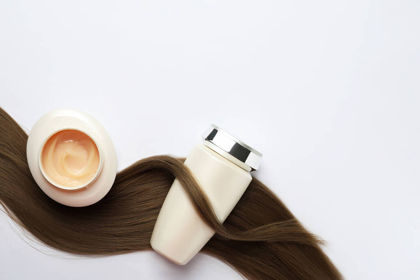 Natural cosmetic products and hair lock on white background, flat lay. Space for text - 写真・画像