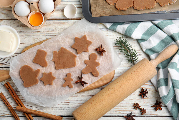 Making Christmas cookies. Flat lay composition with raw dough and ingredients on white wooden table - Foto, afbeelding