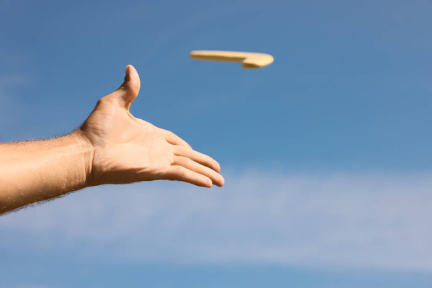 Man throwing boomerang against blue sky, closeup - Foto, Imagem