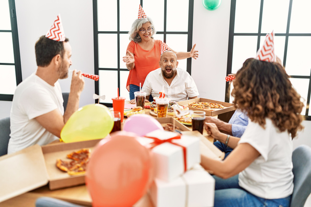 Skupina přátel středního věku se usmívá šťastný oslavit narozeniny doma. - Fotografie, Obrázek