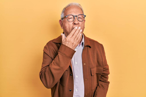 Senior man with grey hair wearing casual jacket and glasses bored yawning tired covering mouth with hand. restless and sleepiness.  - Fotografie, Obrázek