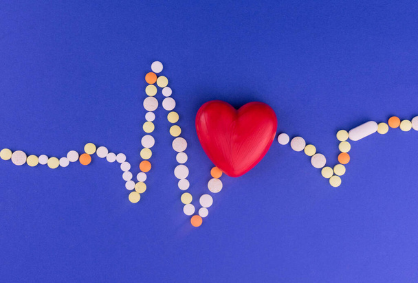 Heart of cardiograms from color pills on a blue background. Concept of heart disease. - Foto, imagen