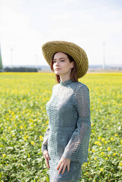 White girl with dark hair standing in yellow blooming field - Fotografie, Obrázek