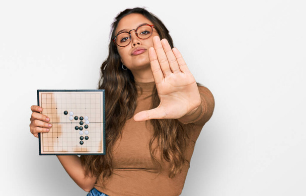 Fiatal spanyol lány gazdaság drauhgts nyitott kézzel csinál stop tábla komoly és magabiztos kifejezés, védelmi gesztus  - Fotó, kép