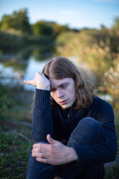 Young european man with long hair with lake behind - 写真・画像