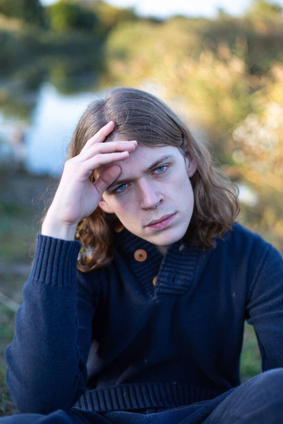 Young european man with long hair with lake behind with blue eyes - 写真・画像
