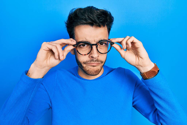 Jeune homme hispanique portant des lunettes sceptique et nerveux, fronçant les sourcils contrariés à cause de problèmes. personne négative.  - Photo, image