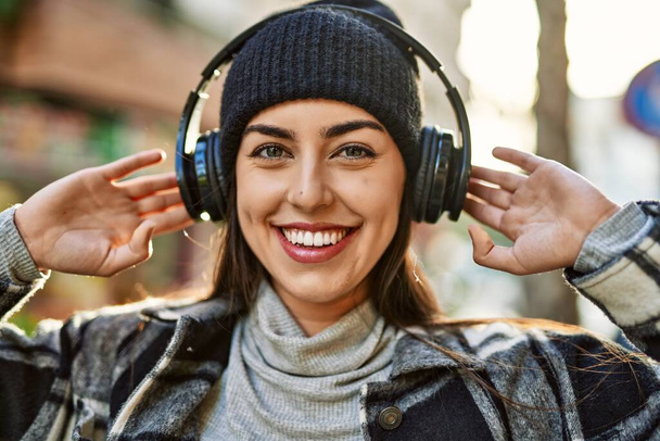 Młoda Latynoska uśmiechnięta szczęśliwa korzystając ze słuchawek w mieście. - Zdjęcie, obraz
