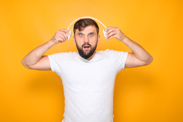 bebaarde man zet een koptelefoon op zijn oren - Foto, afbeelding
