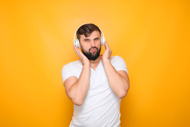мужчина плотно прижимает наушники к ушам, чтобы услышать музыку. - Фото, изображение