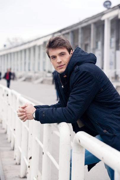Handsome man in jacket leaning on rails - Foto, afbeelding