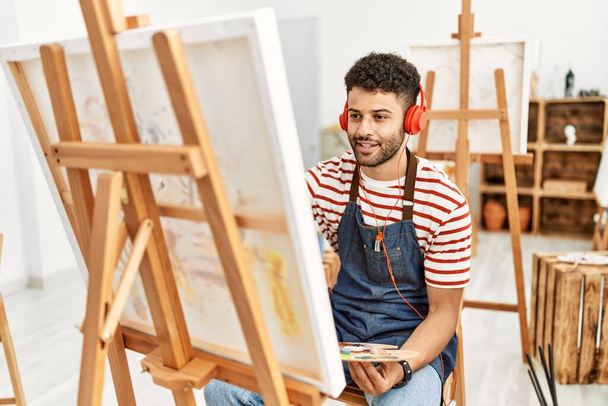 Νεαρός Άραβας καλλιτέχνης άνθρωπος ακούγοντας μουσική σχέδιο στο στούντιο τέχνης. - Φωτογραφία, εικόνα
