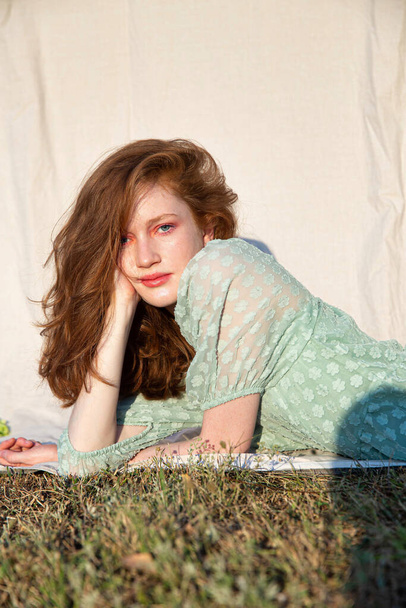 Young white girl in green dress on green grass with red hair - 写真・画像