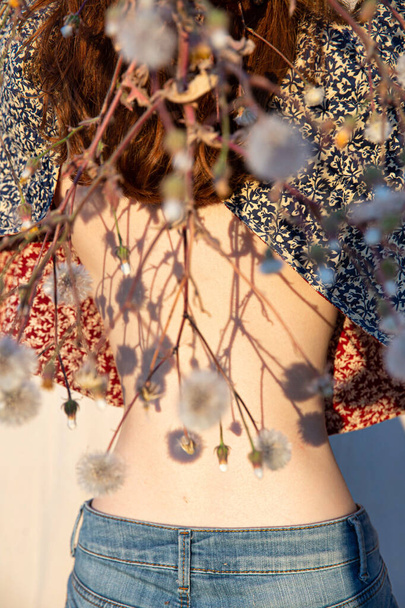 White girl with naked back in jeans with flowers in front - Foto, immagini