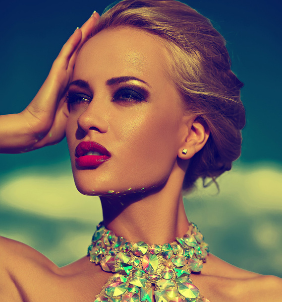 High fashion look.glamor sexy stylish blond young woman model with bright makeup and red lips with perfect sunbathed clean skin with jewelery outdoors in vogue style in evening dress behind blue sky - Фото, зображення