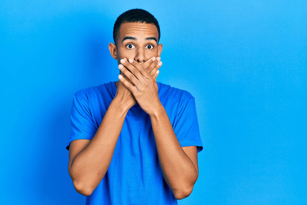 Молодий афроамериканець у блакитній футболці шокований ротом руками за помилку. таємна концепція.  - Фото, зображення