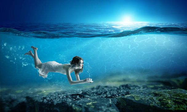 Woman holding a cup underwater - Valokuva, kuva