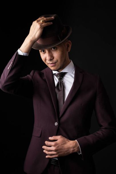 A Caucasian man from Spain in suit on black background with hand on hat - 写真・画像
