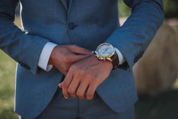 El novio en un elegante traje fijando su reloj - Foto, Imagen