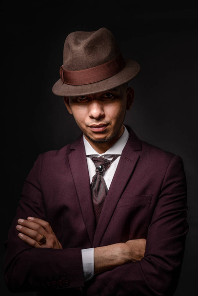 A Caucasian man in suit hiding face behind his hat on dark background. secret and incognito concept - 写真・画像