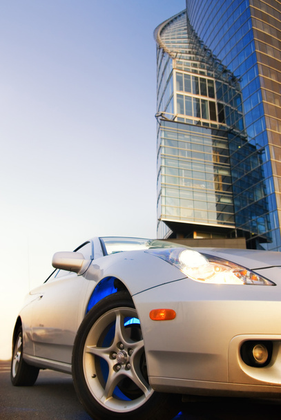 sport auto met kantoorgebouw en heldere blauwe hemel achter het - Foto, afbeelding