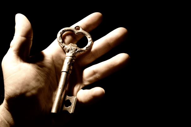 ludzką ręką z stary klucz isolaten na czarnym tle - Zdjęcie, obraz