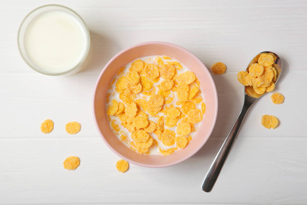  Хрусткі кукурудзяні пластівці з молоком на сніданок на столі крупним планом
. - Фото, зображення