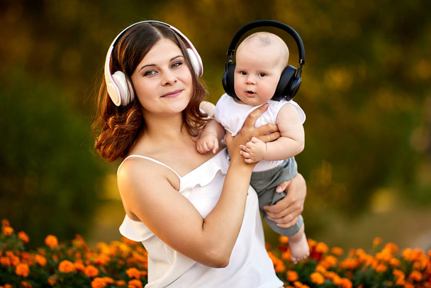Woman and child in cordless headphones walk outdoors. - Fotoğraf, Görsel