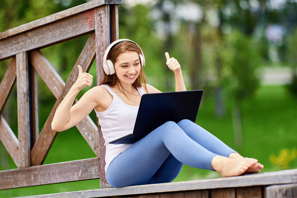 Online education by woman in cordless headphones outdoors. - Photo, Image
