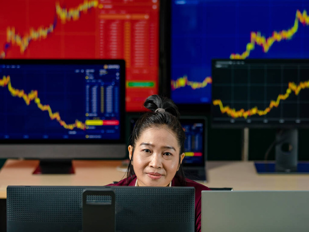 Žena úspěšný profesionální obchodník investor sedět úsměv pohled na kameru obklopen monitorem obrazovky s grafem grafu akcie a Bitcoin kryptoměna analýza růst zpráva v obchodní místnosti. - Fotografie, Obrázek