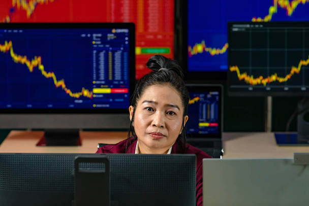 Female successful professional trader investor sit smile look at camera surrounded by computer monitor screen with graph chart stock and bitcoin cryptocurrency analysis growth report in trading room. - Photo, Image