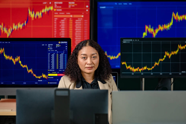 Žena úspěšný profesionální obchodník investor sedět úsměv pohled na kameru obklopen monitorem obrazovky s grafem grafu akcie a Bitcoin kryptoměna analýza zprávy v obchodní místnosti. - Fotografie, Obrázek