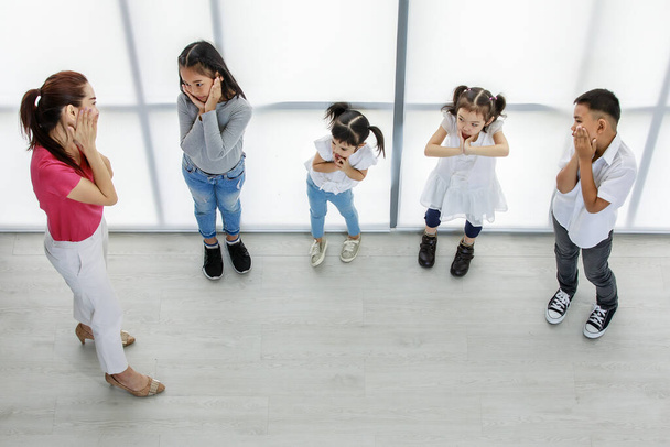 Asyalı kadın ilköğretim okulunun performans öğretmeninin küçük erkek ve kız çocuklarına mutlu bir özel anaokulu oyunculuk dersi verirken en iyi görüntüsü.. - Fotoğraf, Görsel