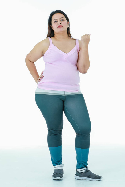 Portrait isolated studio shot of Asian happy healthy strong big fat oversize chubby girl in sport clothing leggings pants standing look at camera smiling posing relax gesture on white background. - Foto, Imagem